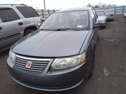 Grey Saturn Ion sedan with cloudy headlights in salvage lot.