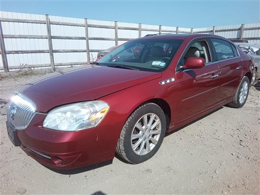Dark red Buick Lucerne sedan parked on a gravel lot.